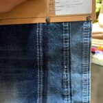 Dark blue 12.5 Oz denim fabric sample showing faded wash effects and stitching details, SKU PRD-1.